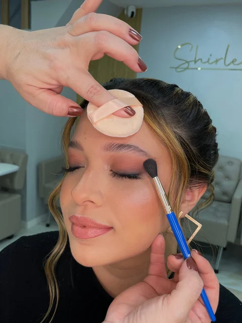 Maquiagem sendo aplicada em cliente, com sombra nos olhos
